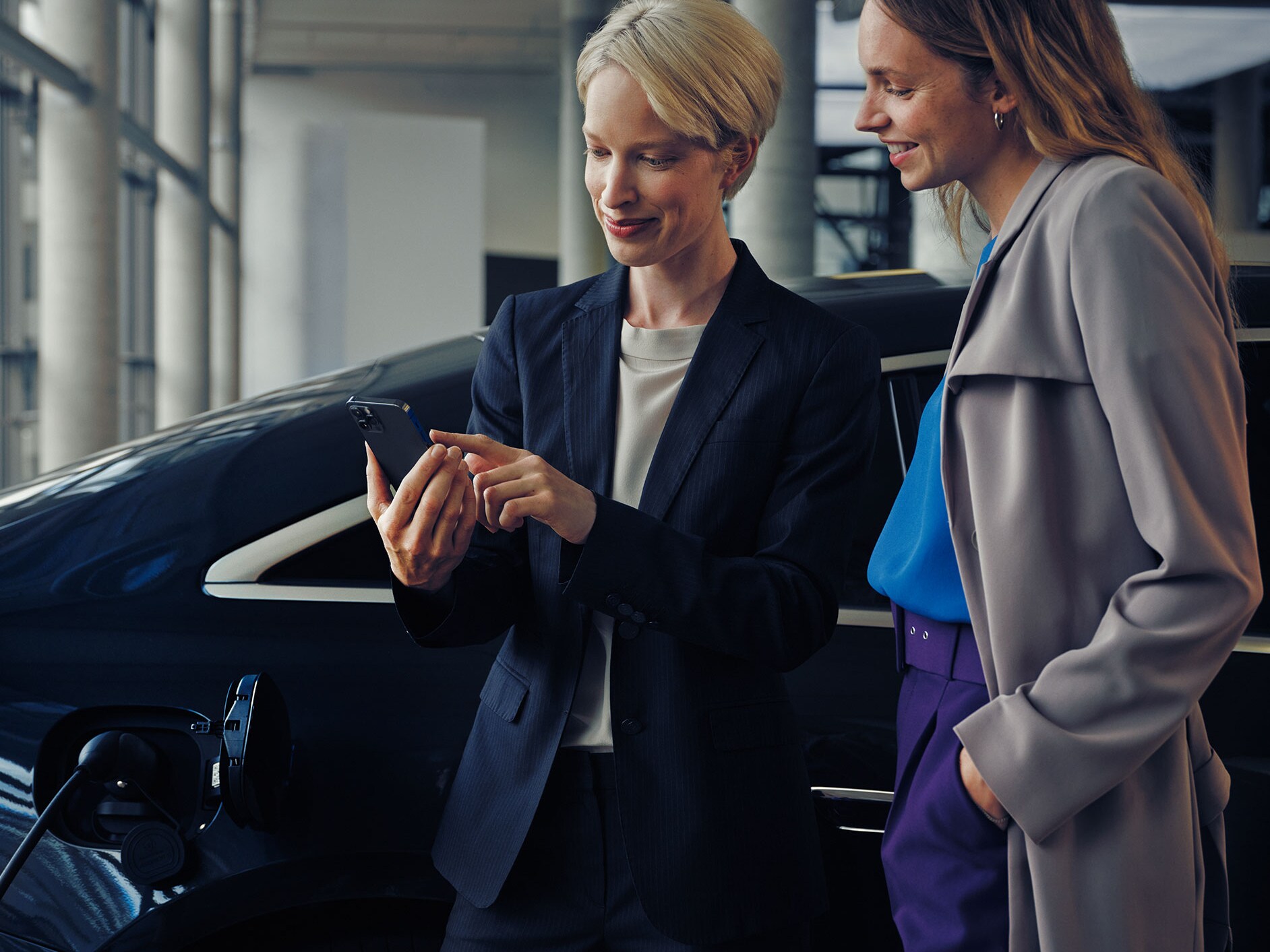 Two women in front of a charging EQE Saloon.