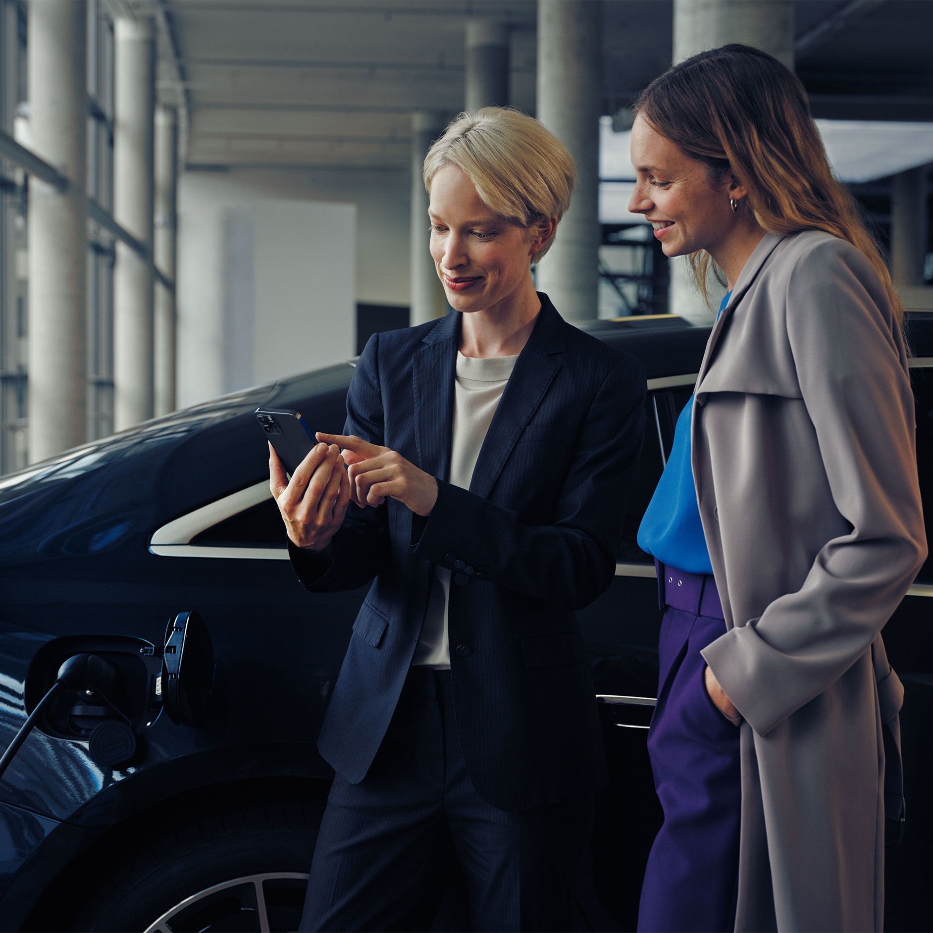 Installation consultation | Charging | Mercedes-Benz Two women in front of a charging EQE Saloon.