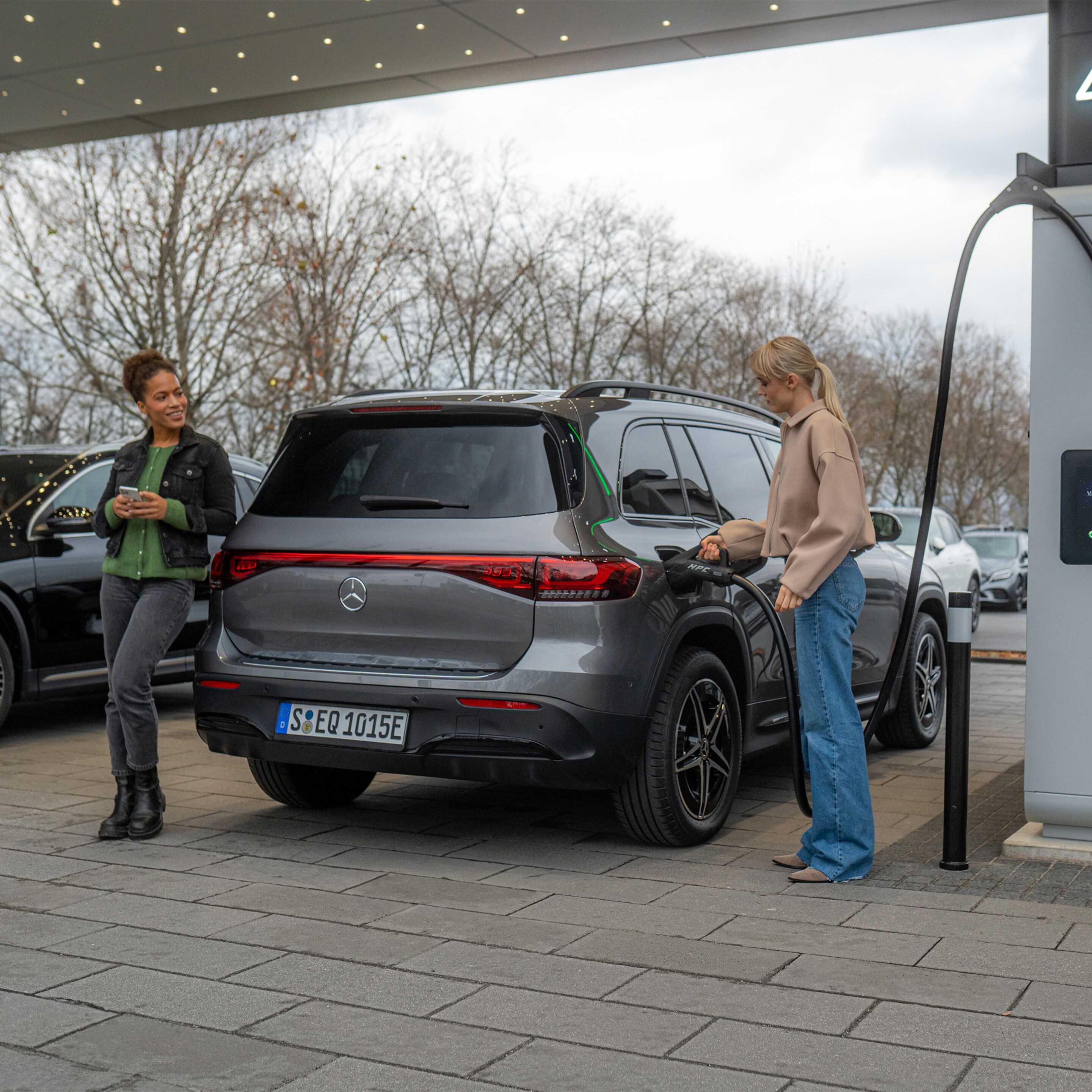 Two Mercedes-Benz electric cars at a charging station.
