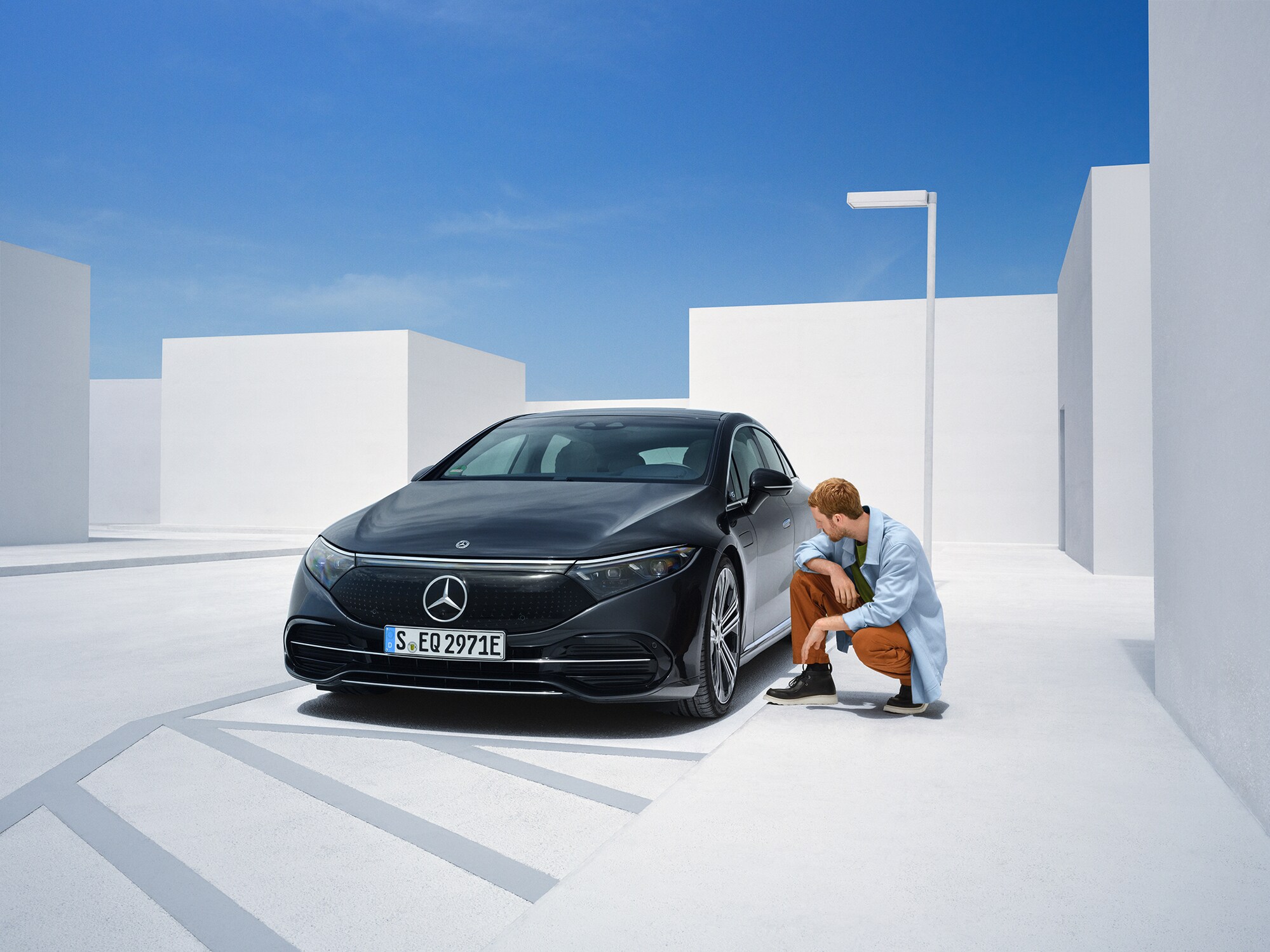 Man is kneeling on the side of his Mercedes-Ben to check on it
