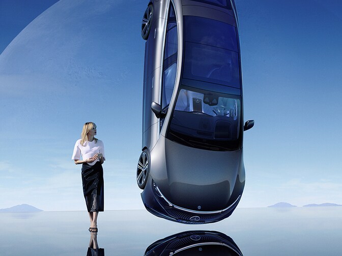 A woman stands right beside a hovering Mercedes-Benz car.