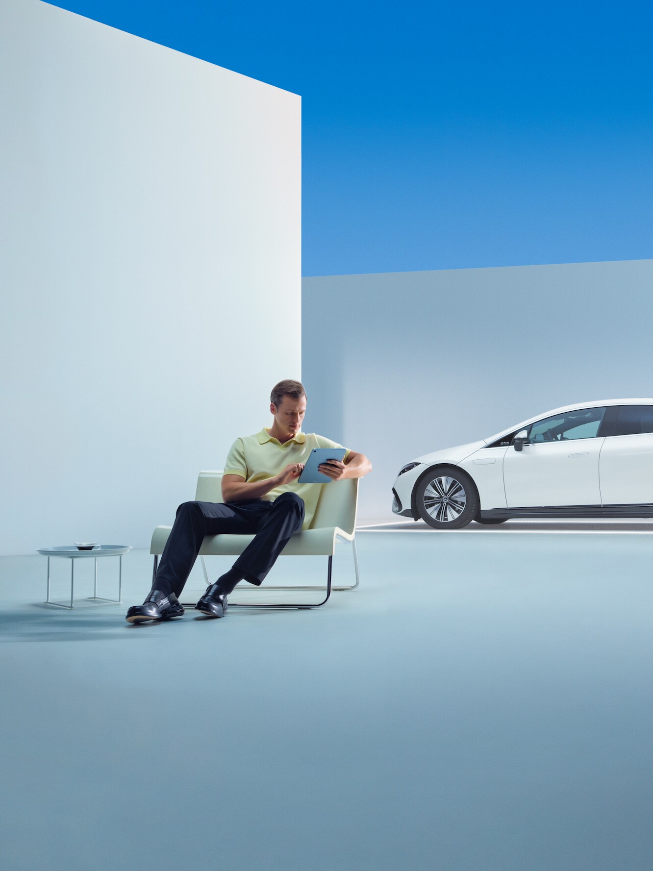 A relaxed man is sitting in front of his Mercedes with his tablet.