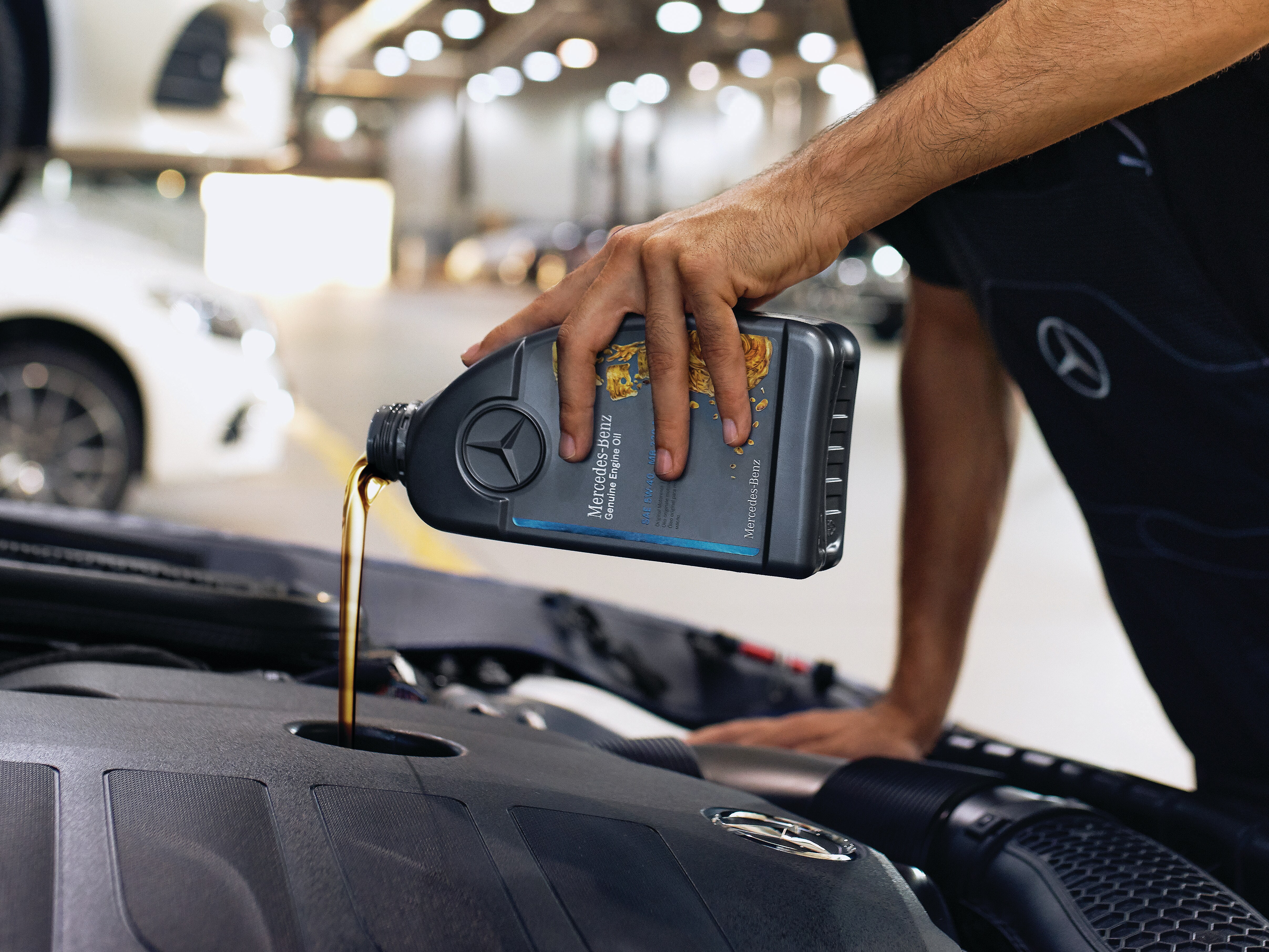 Close‑up of engine bay with Mercedes‑Benz genuine engine oil being poured.