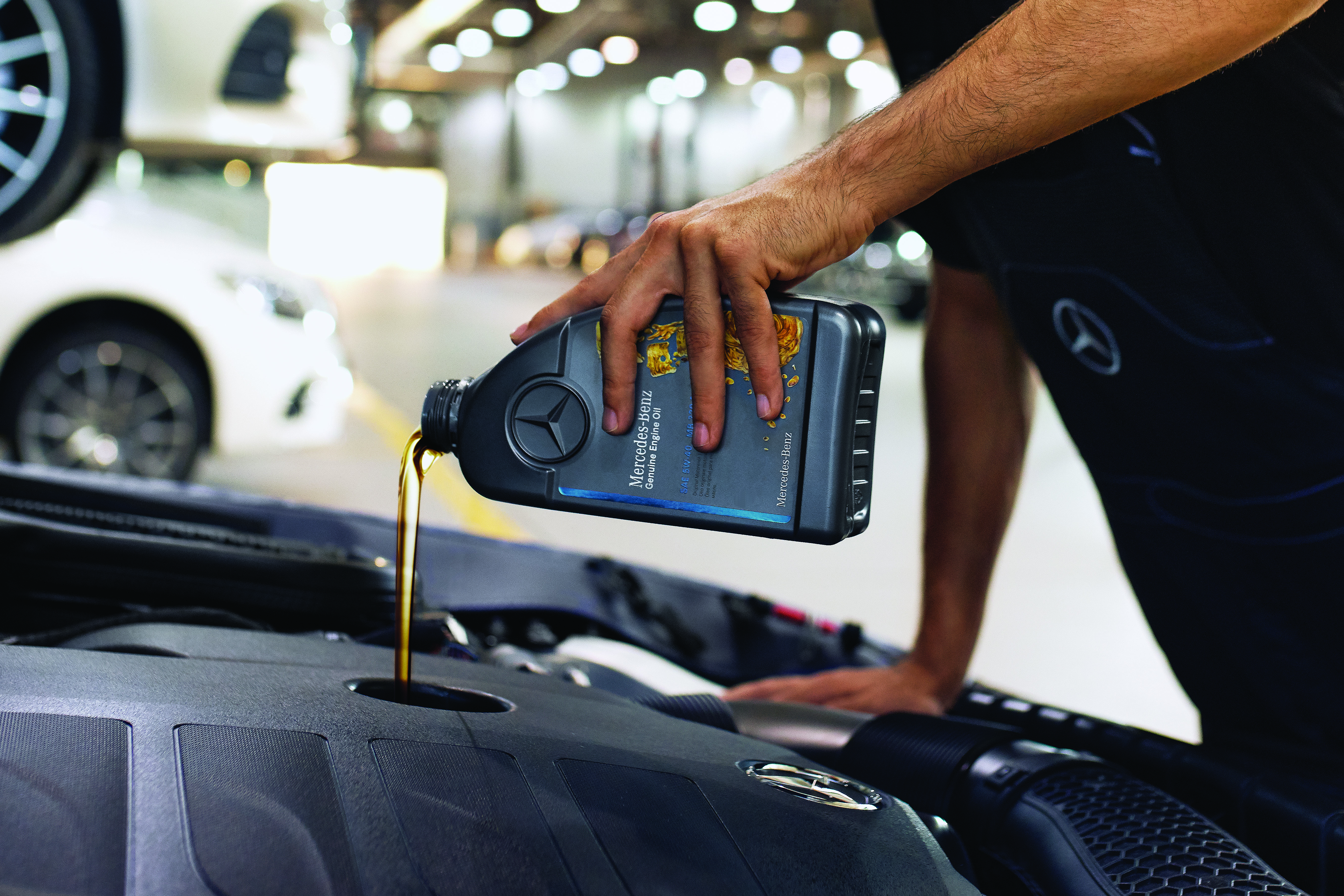 Mercedes-Benz Genuine Engine Oil Close‑up of engine bay with Mercedes‑Benz genuine engine oil being poured.
