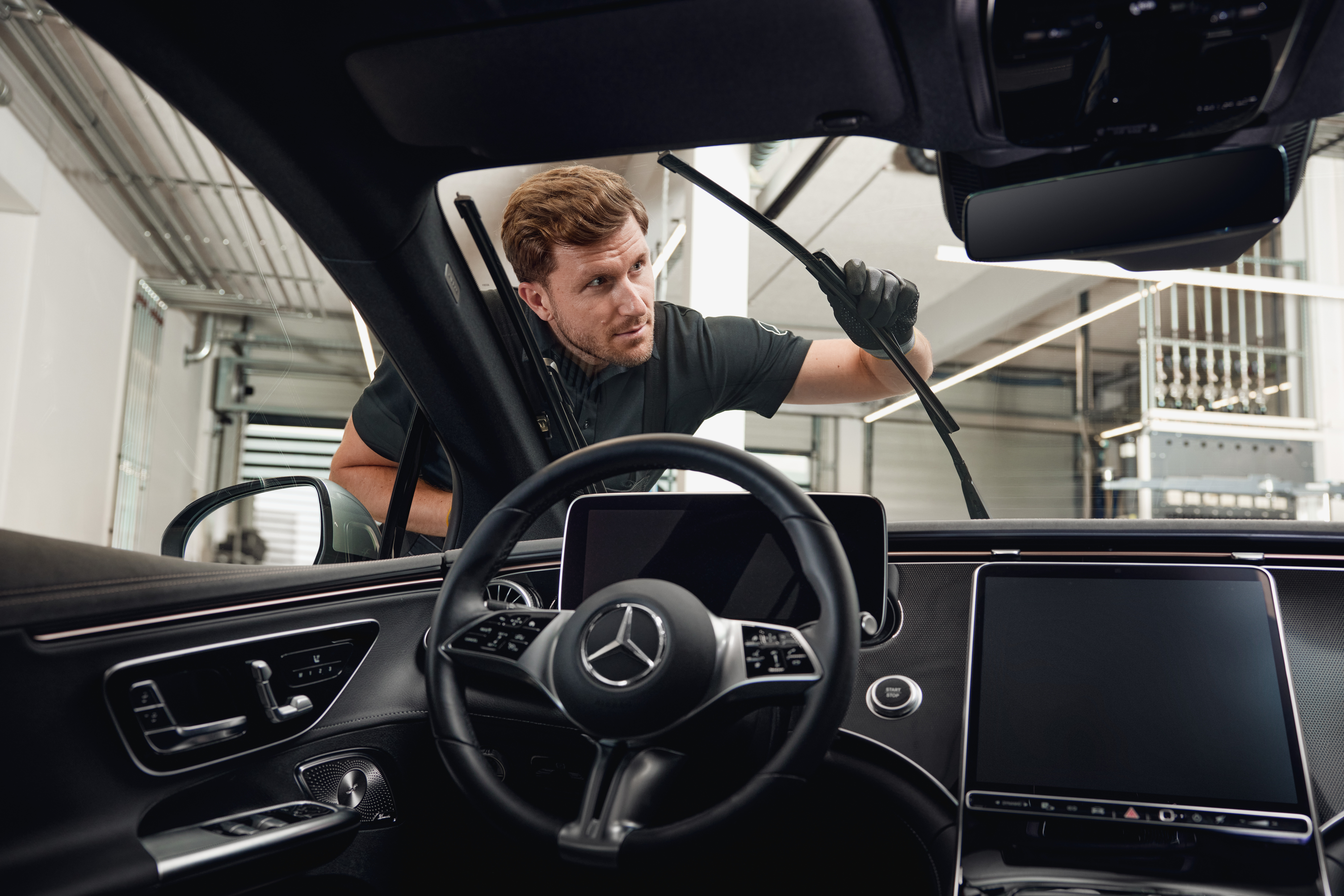 Mercedes-Benz Genuine Wiper Blades Interior view of a Mercedes‑Benz vehicle with a technician exchanging genuine wiper blades.