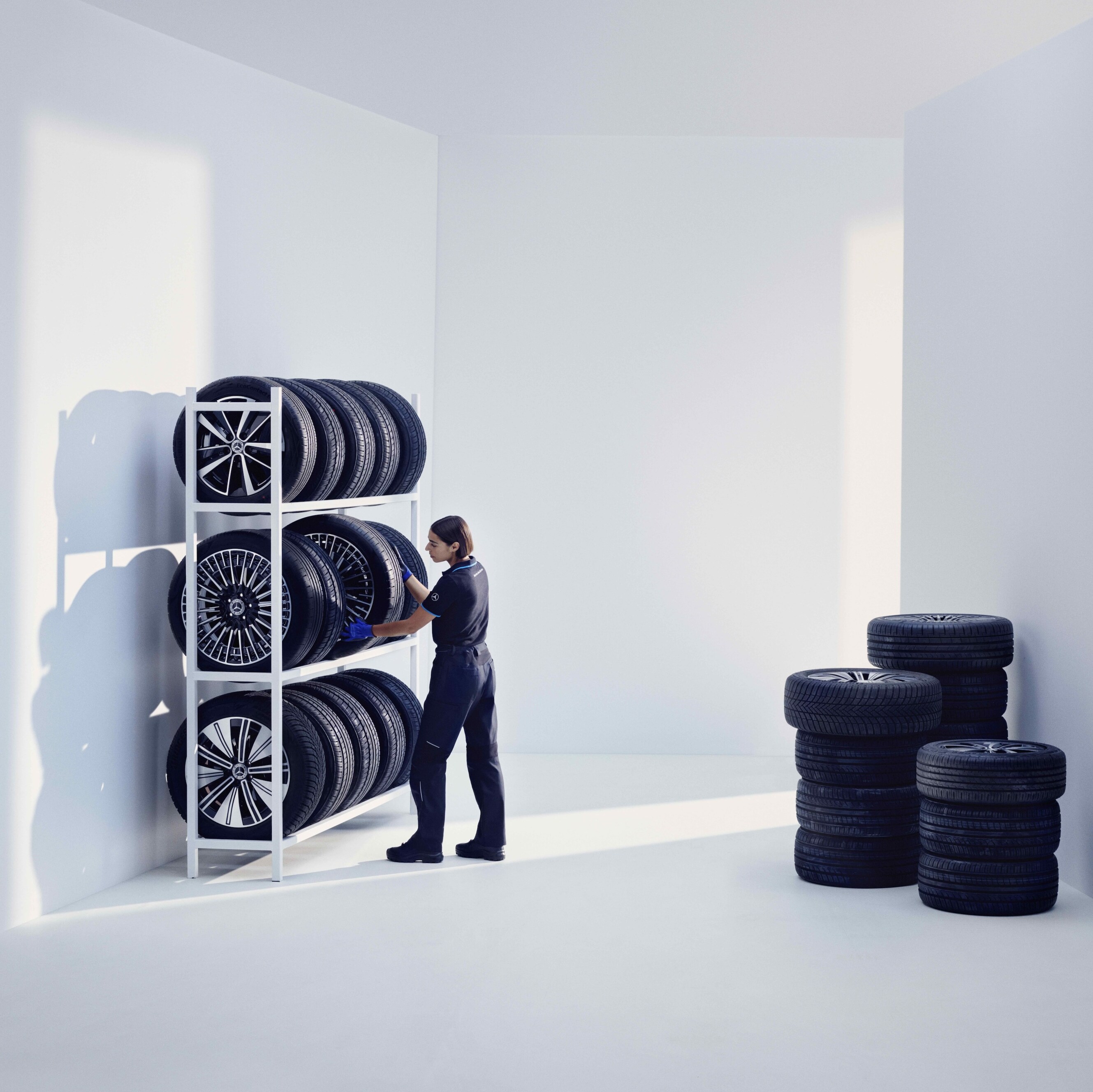 A Mercedes-Benz technician stores Mercedes-Benz Original tires on a shelf.