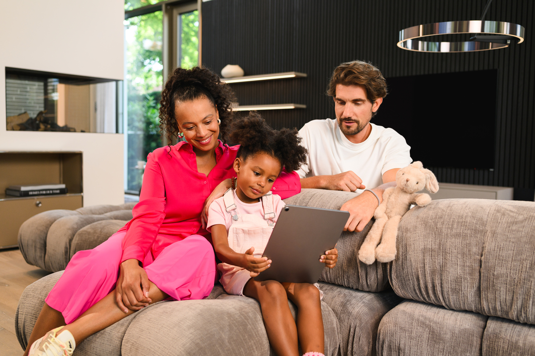 Mercedes-Benz Insurance | Insurance A family sitting on the couch looking at a tablet in the little girls hands