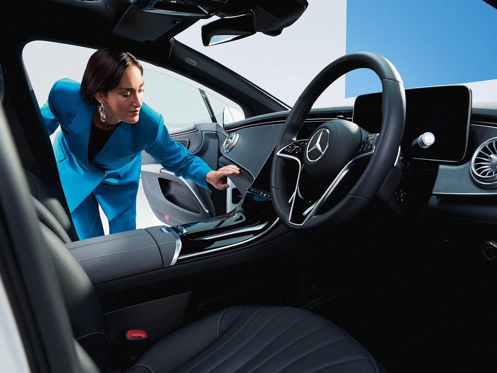 Woman in a blue blazer looking inside the car 
